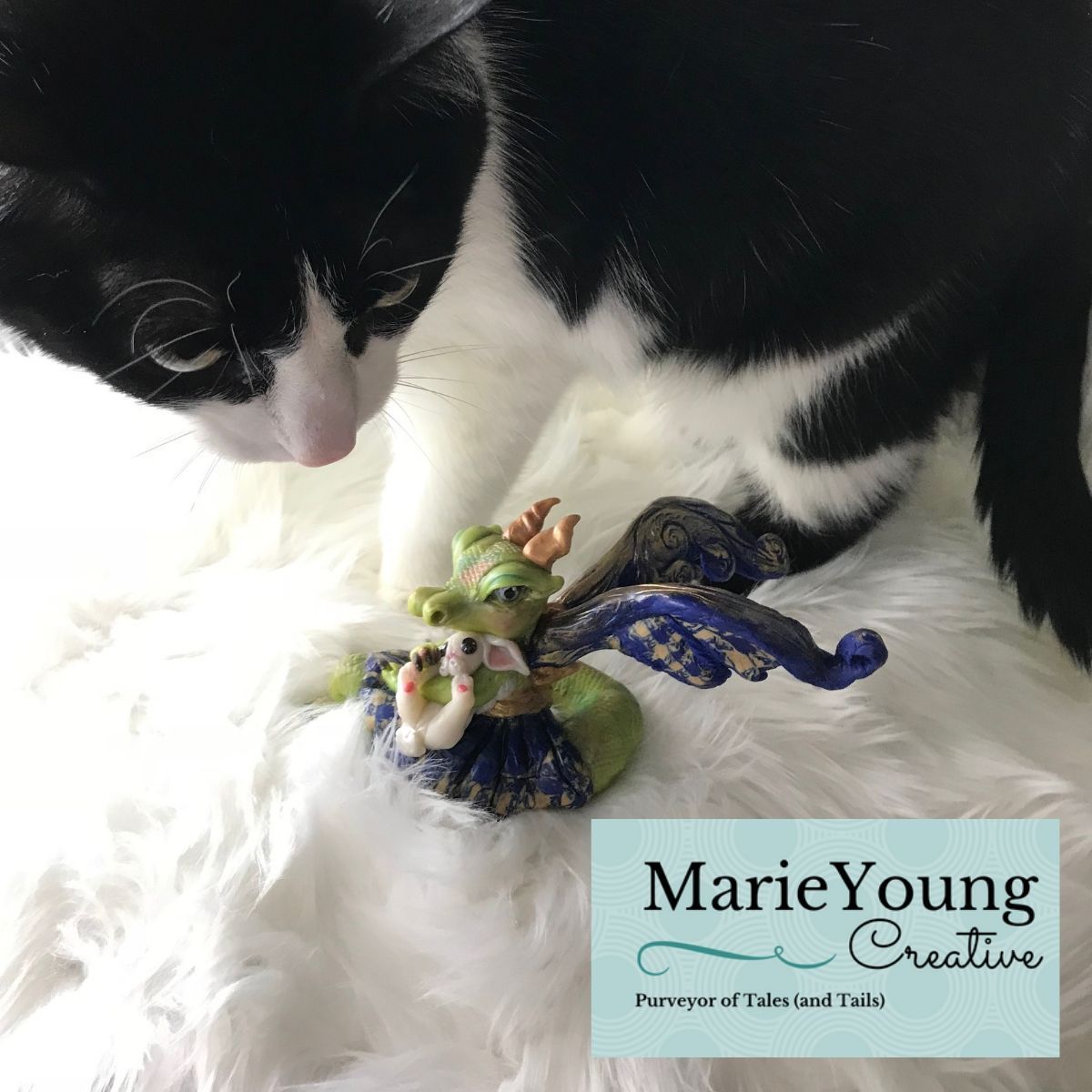 Black and white cat sniffing dragon sculpture